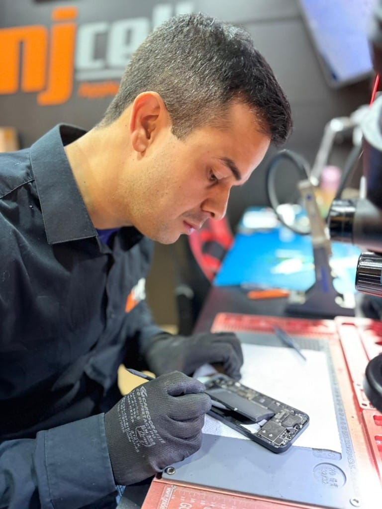 Técnico da NJCELL realizando troca de bateria de iPhone em Sorocaba