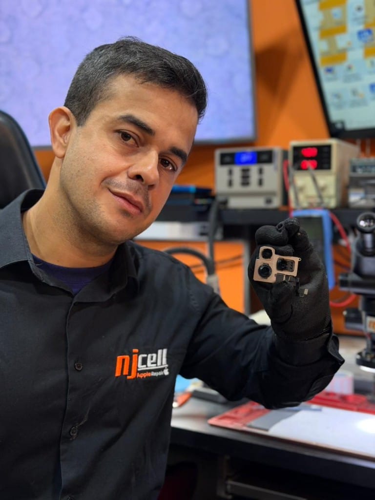 Troca de câmera iPhone Sorocaba - NJCELL Técnico da NJCELL segurando módulo de câmera de iPhone para troca em Sorocaba